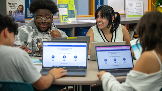Students seated at a round table using laptops