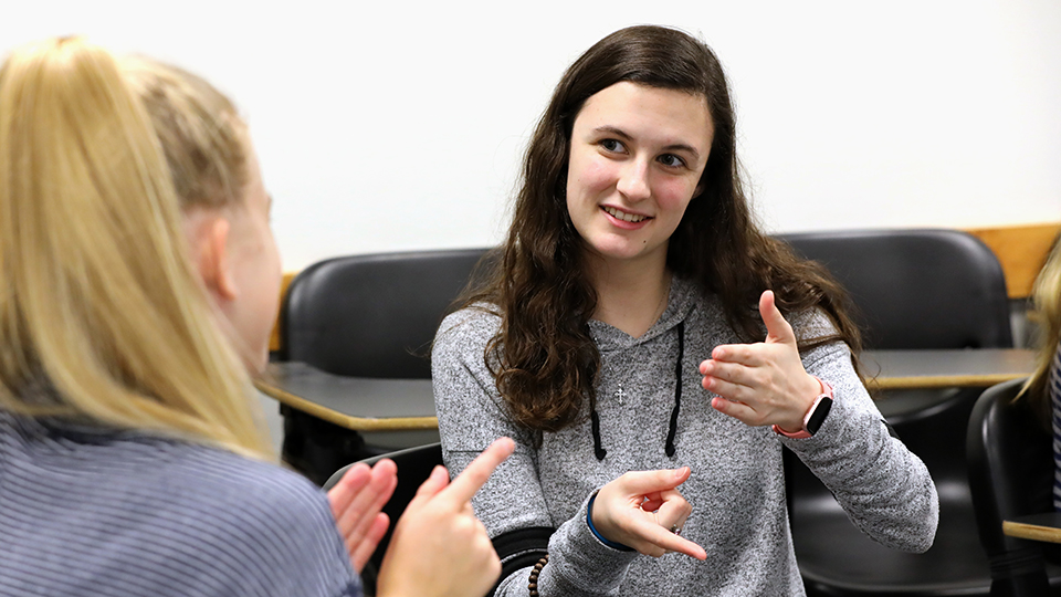 Two students converse using sign language.