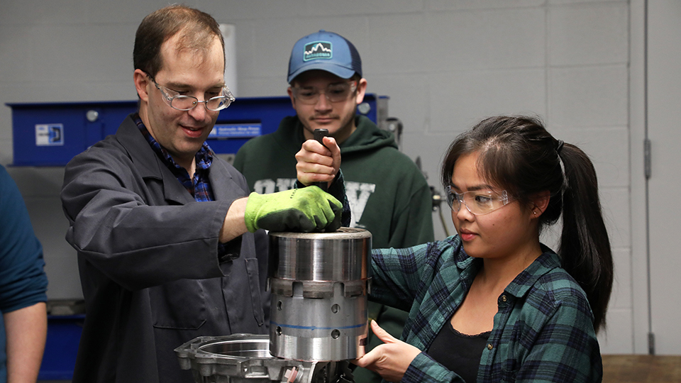 Three students working on a car part in the JCCC automotive lab