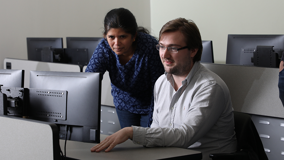 A student and instructor working together on a computer.
