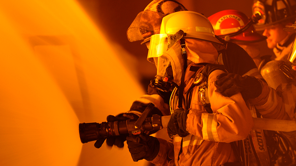 A firefighter in full gear sprays a hose.