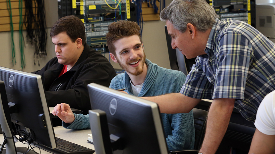 Two students working with their instructor in a networking class