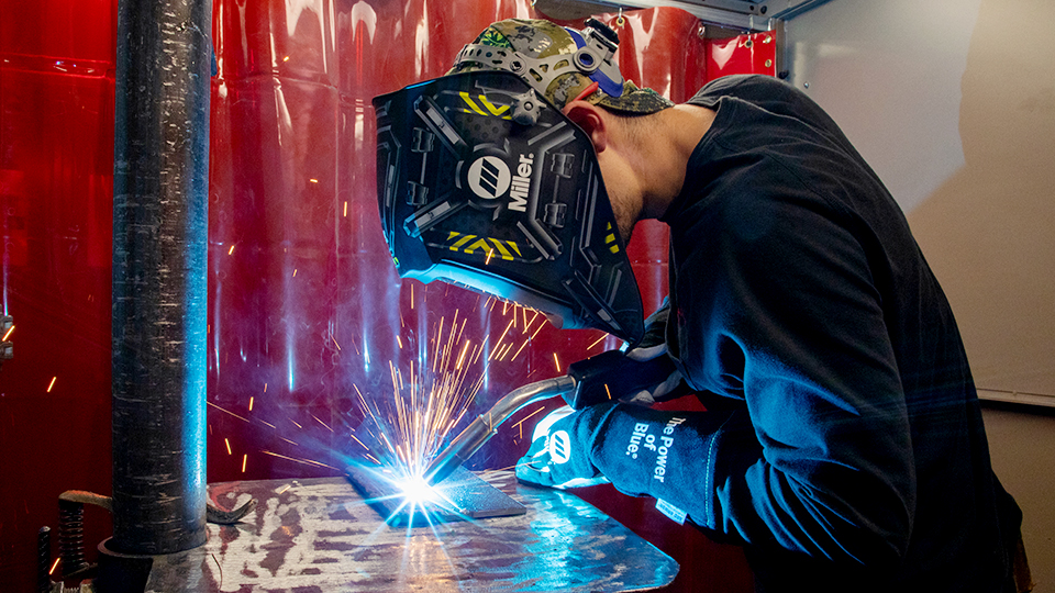 A jccc student wearing safety gear practices a weld in the lab