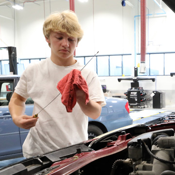 a young man checking the oil on a dipstick