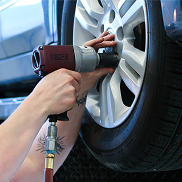 A JCCC student tightens lug nuts on a car wheel