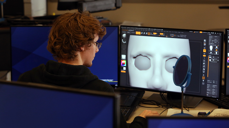 Student working in the animation lab showing his art on a computer monitor