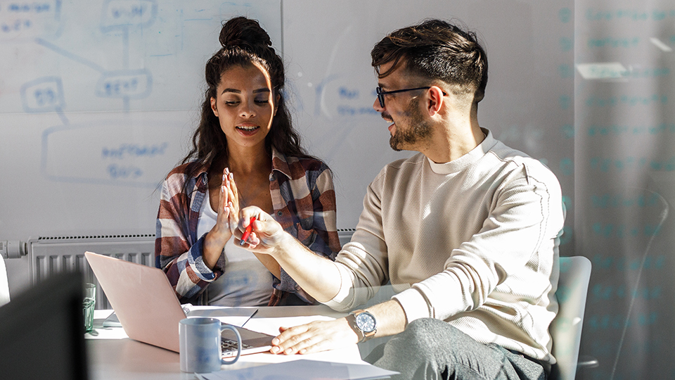 Two students, sitting at a table, doing a group project