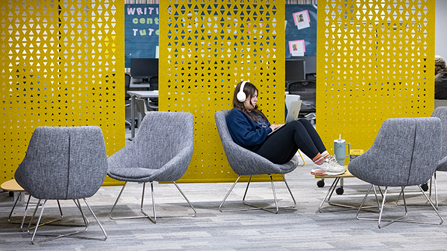 Student in a study space, wearing headphones, working on a laptop