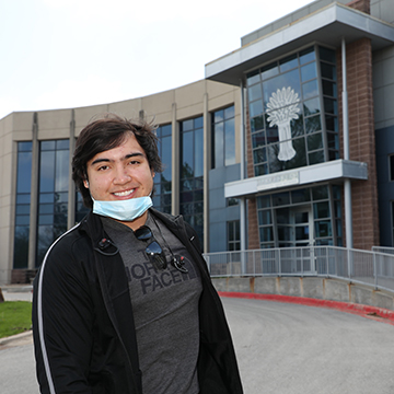 JCCC honors student wearing a face mask posing in front of Harvesters food bank