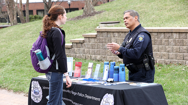 Student speaking with a police officer at a table during Cav Craze